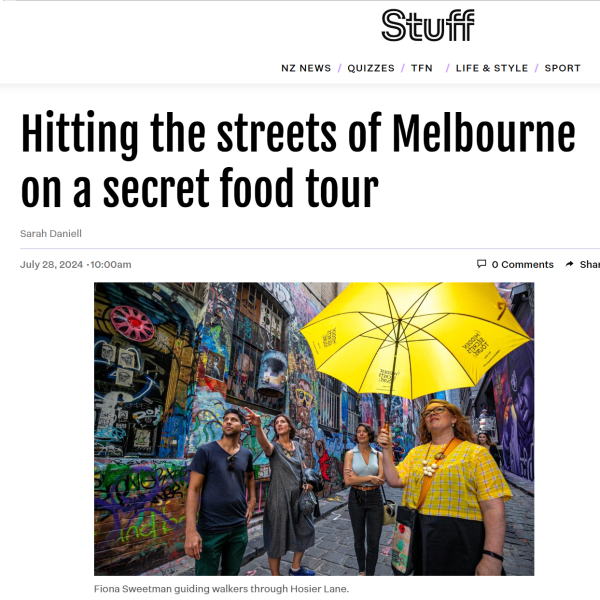 Screen shot of the NZ online article, including a picture of tour group in a graffiti lane. The guide holds a yellow umbrella.